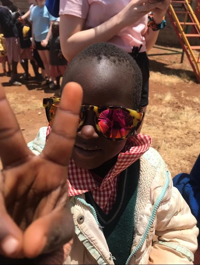 A child in sunglasses holding up a peace sign