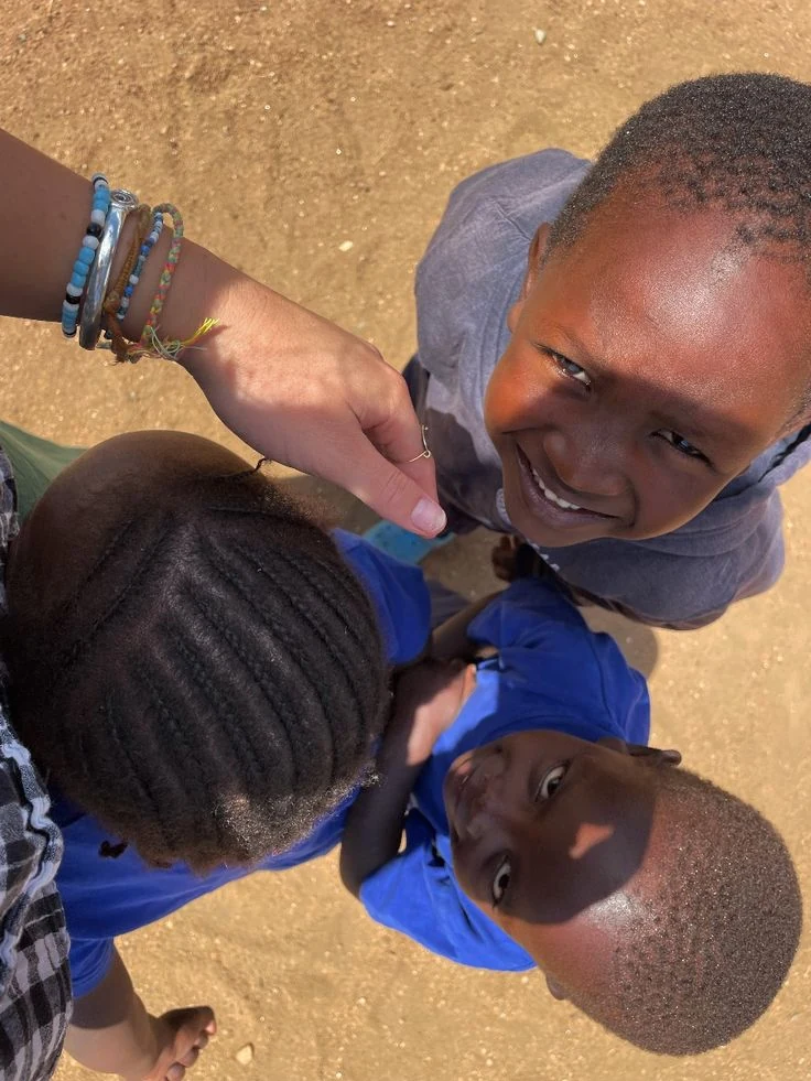 Three smiling children gathered in a circle outdoors